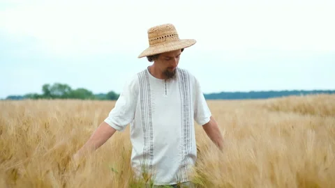Stylish farmer of Caucasian appearance with a hat and beard walks in the field Stock Footage 135408698