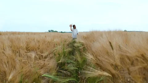 Stylish farmer of Caucasian appearance with a hat and beard walks in the field Stock Footage 135409600