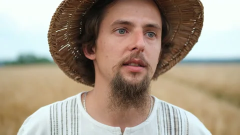 Stylish farmer of Caucasian appearance with a hat and beard walks in the field 스톡 동영상 135589715