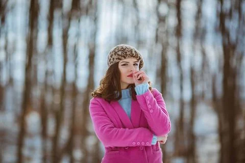 A stylish female in a leopard pattern beret and a pink coat smoking a cigaret Foto stock