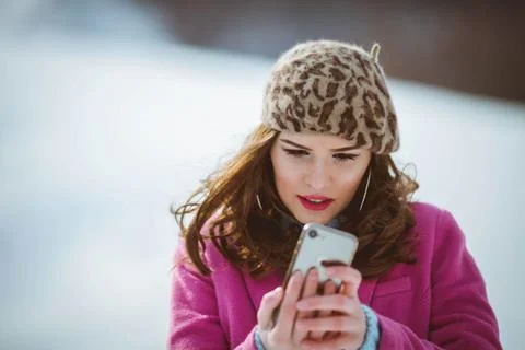 Stylish female in a leopard pattern beret and a pink coat doing a selfie Stock Photos