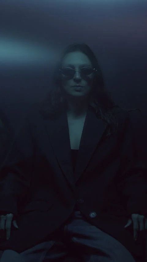 Stylish Female Model in Jacket and Sunglasses under Colorful Studio Lighting Stock Footage 335891128
