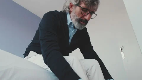 Stylish good looking mature man putting on his casual comfort shoes in front of Video stock 229507281