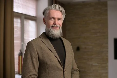 Stylish gray-haired man with a beard in a jacket looks confidently Stock Photos
