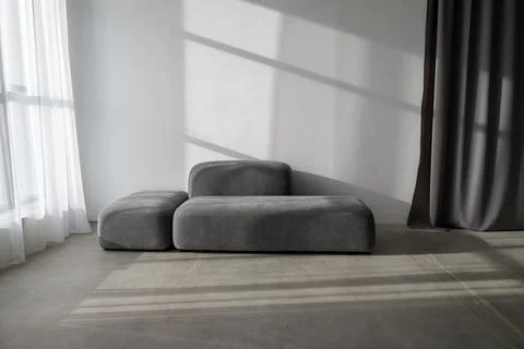 Stylish grey sofa in the loft with a window shadow on the wall Stock Photos