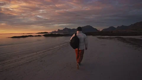 Stylish guy with backpack walks along the coast by the sea. Autumn mood. sunset Stock Footage 219029161