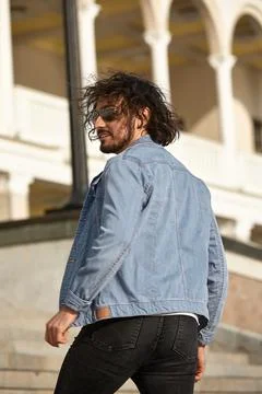A stylish guy with glasses stone wall on the background and looks away. strong Stock Photos