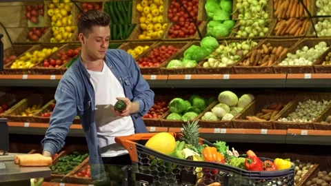 Stylish guy selecting fresh marrow at the supermarket Video stock 311985141