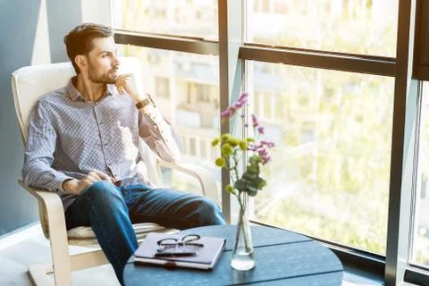 Stylish guy sitting against window Stock Photos