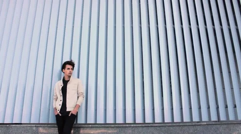 Stylish, handsome guy in a hat waiting for a friend. The street is cool and Stock-Footage 54684617