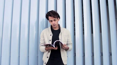 Stylish, handsome man in the hat is reading a glossy magazine while standing in Stock-Footage 54684337