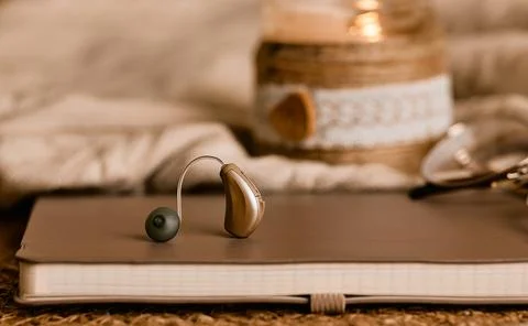 Stylish hearing aid on a soft notebook showcases innovative solutions in audi Fotos de archivo