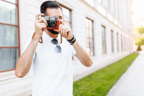 Stylish hipster with a beard and a camera, taking pictures, walking around th Stock Photos