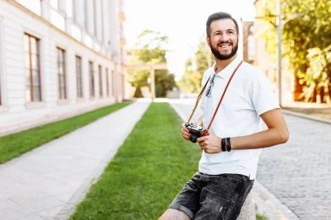 Stylish hipster with a beard and a camera, walking around the city with a cam Stock Photos