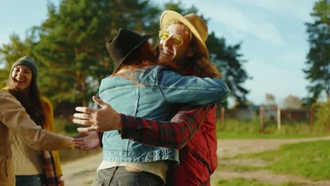Stylish hipster friends met eath other in nature. Four young people hug smiling Stock Footage 143040021