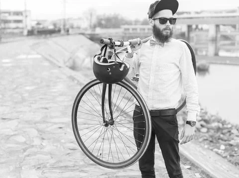 Stylish hipster guy posing with his bicycle - black and white photograph. Stock Photos