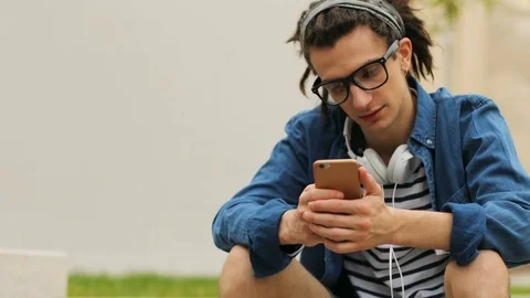 Stylish hipster man with dreadlocks using smart phone for surfing in the Stock Footage 79441246