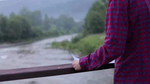 Stylish hipster traveler exploring map at sunny forest and lake in the mountains Stock Footage 67807960