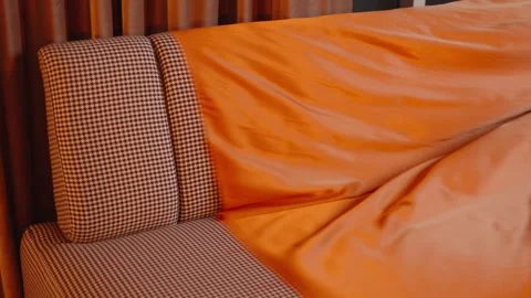 Stylish houndstooth chair elegantly adorned with a luxurious orange satin sheet, Stock Footage 262630228