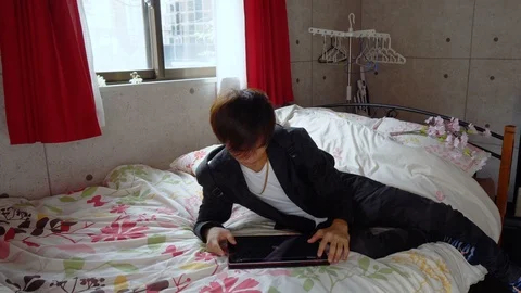Stylish Japanese Man Using Tablet Computer in Bed Stock Footage 104477510