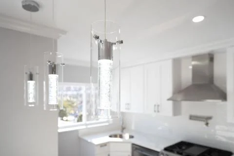 Stylish kitchen featuring modern pendant lighting with cylindrical glass sh.. Stock-Fotos