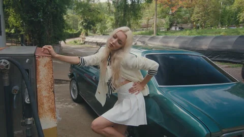 A stylish lady striking a pose beside an oldfashioned car in a city environment Stock Footage 279386885