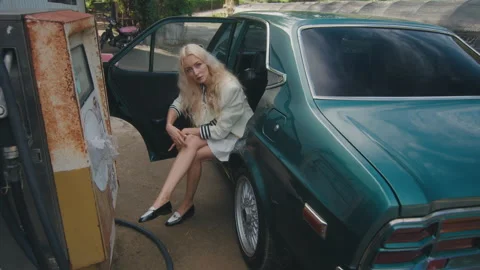 A stylish lady striking a pose beside an oldfashioned car in a city environment Stock Footage 279387723