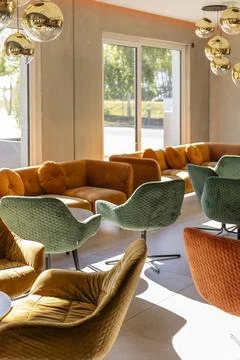 A stylish lounge showcases an array of plush chairs in warm colors, with gold Stock Photos