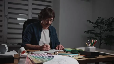 A stylish male architect is working on creating a project. The specialist is Stock Footage 297050744