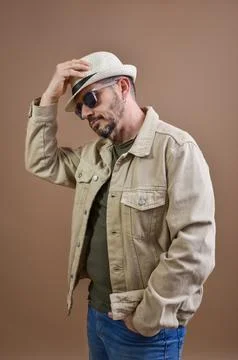 Stylish man adjusting his hat and posing in studio Stock Photos