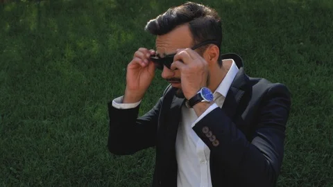 Stylish man with a beard in a classic suit puts on sunglasses drinks coffee Stock Footage 113903885