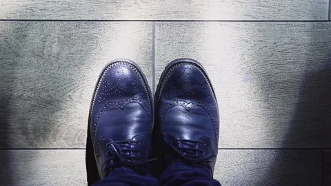 A stylish man in blue leather elegant men's shoes stands on a beautifulul Stock Footage 124716362