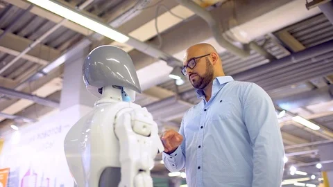 A stylish man communicates with a robot, presses a plastic mechanical arm to the Stock Footage 86450608
