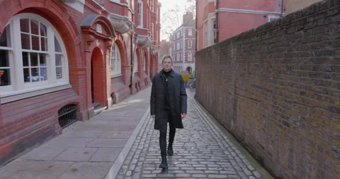 A Stylish Man with a Confident Stroll is Walking in a Charming Historical Vídeo Stock 307540990