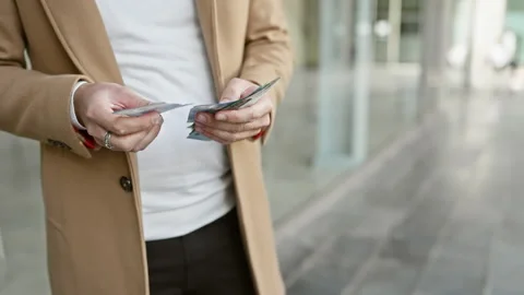 A stylish man counting malaysia ringgit bills on a city street, depicting c.. Stock Footage 275414850