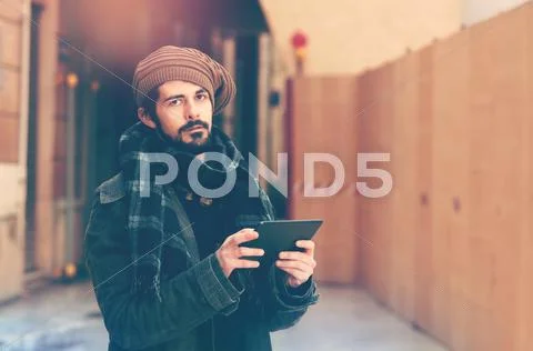 Stylish man enjoying the free internet using tablet in warm tone filter appli Stock Photos