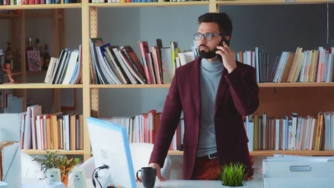 Stylish man in glasses and a beard emotionally talks on the phone Stock Footage 87977445