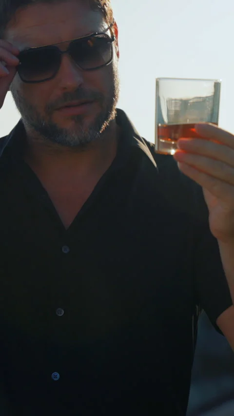 Stylish man jacket and sunglasses holding glass of whiskey Stock Footage 295165911