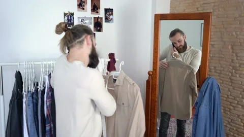 Stylish man  is looking in a mirror Talking on the smartphone Choosing shirt Stock Footage 147892764