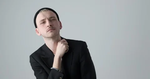 Stylish man posing in black blazer and knit hat over white background Video stock 105185353