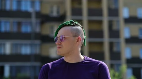 Stylish man with problematic skin in sunglasses standing on street. Side view of Stock Footage 204037178
