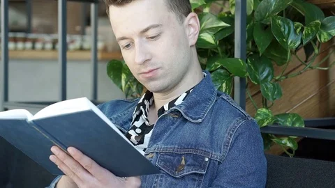 Stylish man reading book in the cafe and smiling to the camera, steadycam shot Stock Footage