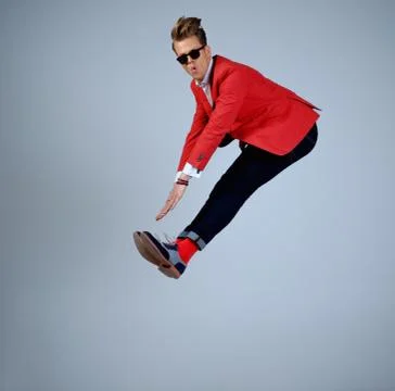 Stylish man in red jacket having fun jumping Stock Photos