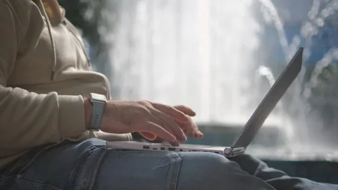 Stylish man sitting under park tree with laptop. Relaxed man using wireless Video stock 252203699