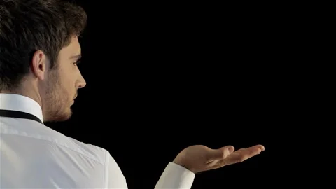 Stylish man stands backwards, gesturing with palm against black background Stock Footage 311918653