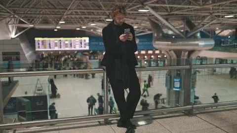 Stylish man using his smartphone at the airport terminal Stock Footage 328549307