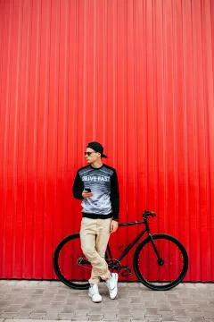 Stylish man using a mobile phone standing near his bike Stock Photos