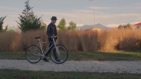Stylish man walking next to a Bicycle in the Park. Walk through the Park by bike Stock Footage 121808460