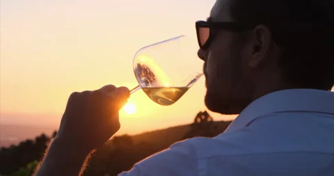 Stylish man in a white shirt is testing a new sort of white wine from a glass Video stock 204142887