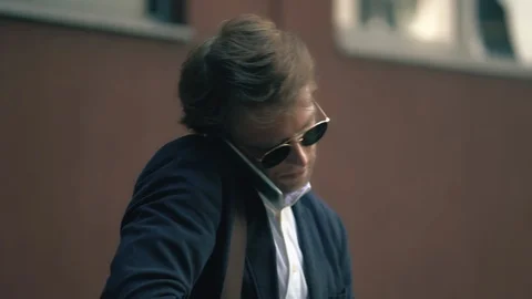 Stylish Man Is Writing Something In His Notebook While Speaking on Cellphone Stock Footage 126128211
